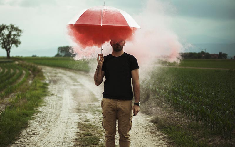 A man holding an umbrella with smoke coming out of it.