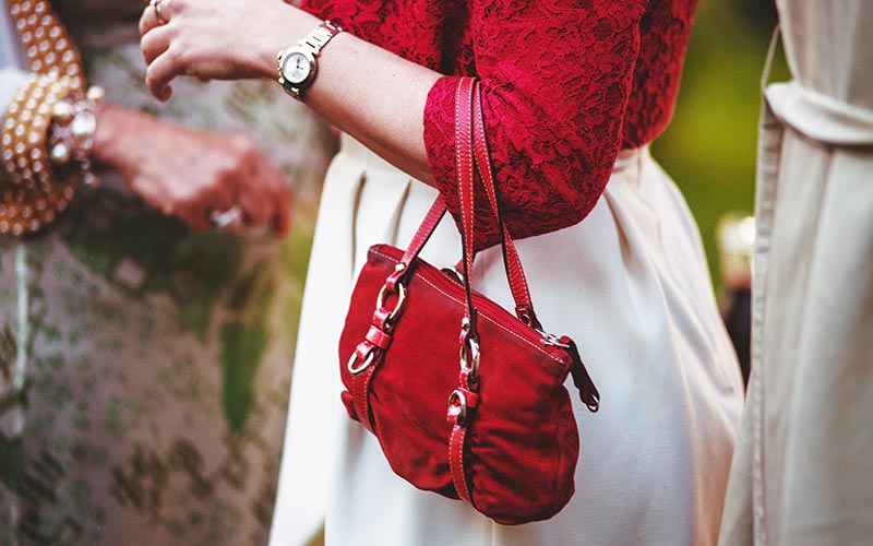 A woman holding onto her purse while wearing a watch.