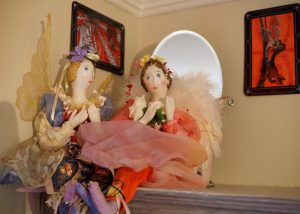 Two dolls are sitting on a table in front of a mirror.