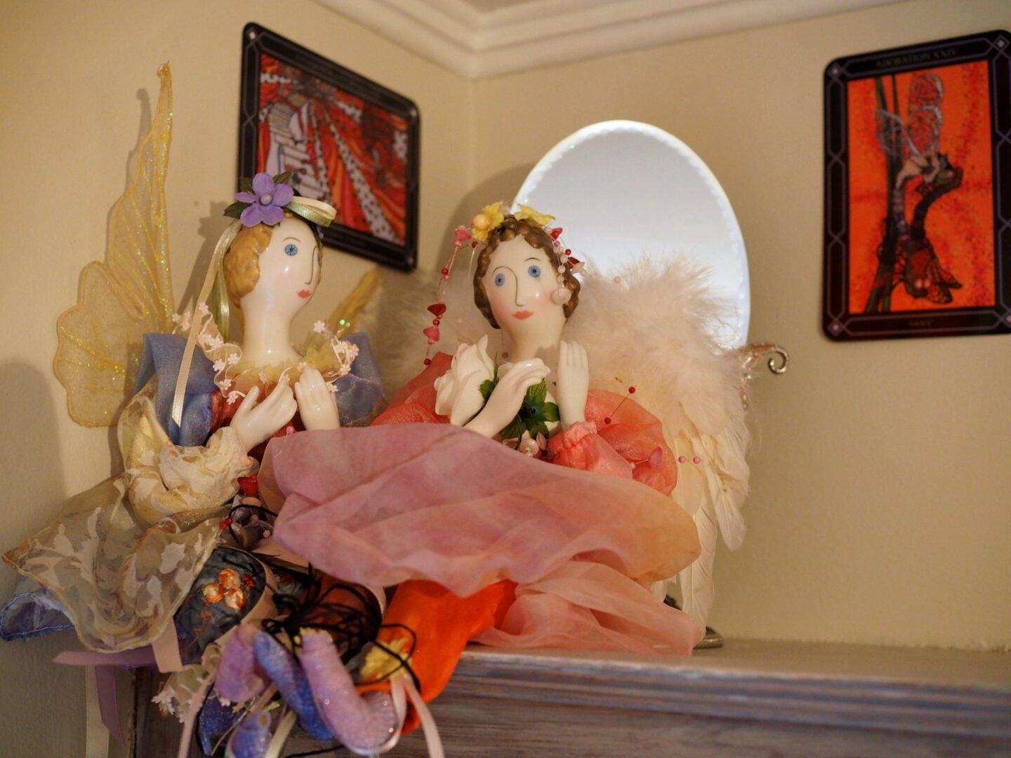 Two dolls are sitting on a table in front of a mirror.